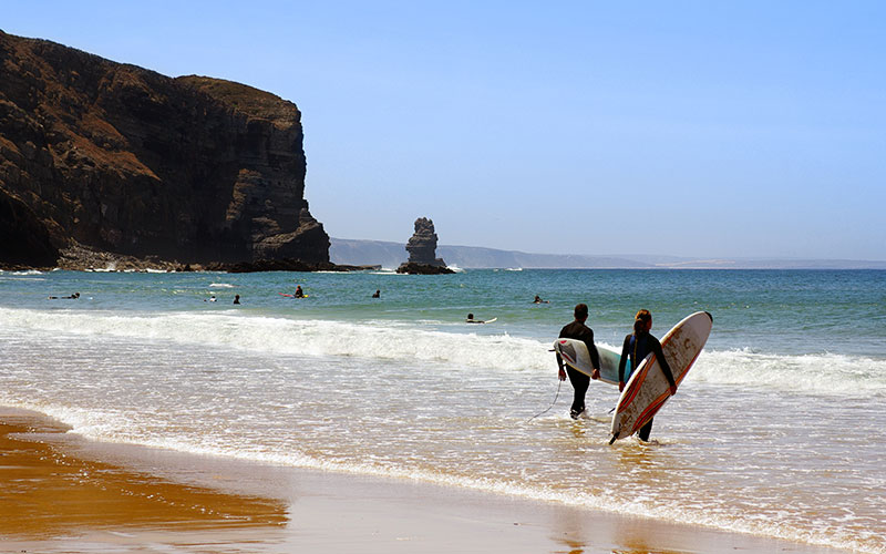 Two surfers ready to enter the sea in Arrifana Beach, Algarve Portugal